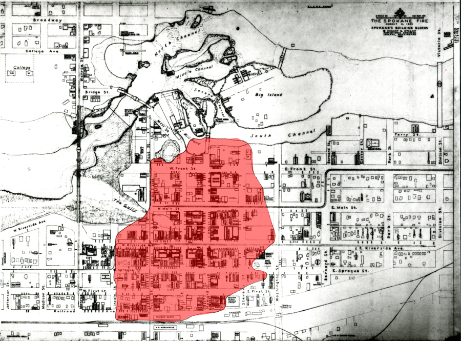 A map depicting a town layout with streets labeled, including Broadway, Bridge St., W. Front St., W. Main St., and W. Riverside Ave. A red shaded area highlights a section of the map, encompassing multiple blocks. The map includes water channels labeled North Channel, Middle Channel, and South Channel, as well as Big Island and sections of land. The title reads "The Spokane Fire" with additional text about Spokane's building blocks.