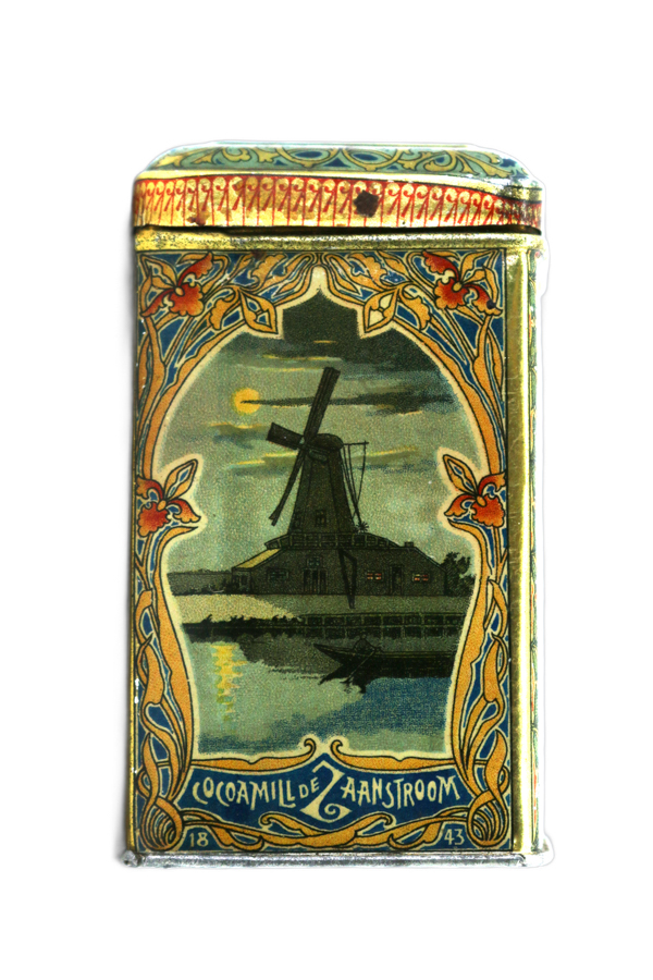 A decorative tin featuring an illustration of a windmill by a waterway under a moonlit sky. The border is adorned with intricate floral patterns. Text at the bottom reads "Cocoamill de Zaanstroom" with the numbers 18 and 43 on either side.