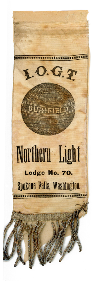 A fabric banner with fringe at the bottom. Text on the banner reads: "I.O.G.T." followed by an image of a globe with the words "Our Field" across it. Below the globe, it says "Northern Light" and "Lodge No. 70." The location given is "Spokane Falls, Washington."