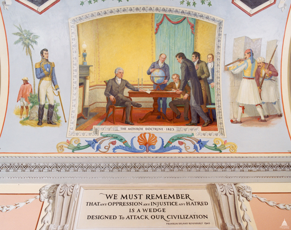 A historical mural depicting a scene from the era of the Monroe Doctrine in 1823. Several men in 19th-century attire are gathered around a table with one man pointing at a globe. To the left, a military figure stands with a sword and another person stands beneath a palm tree. To the right, two men in traditional attire carry rifles. Below the mural reads, 