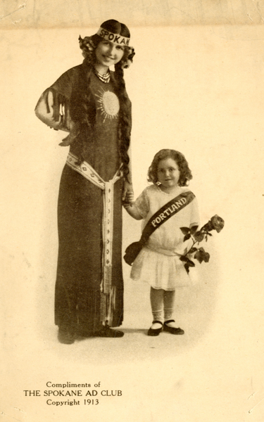 A woman dressed in a decorated long dress stands holding hands with a young girl. The woman wears a headband labeled 