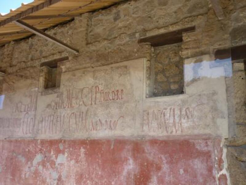 Photograph of the Celadus inscription on a Pompeii wall, with red painted letters across plaster.